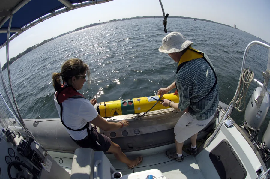 Two researchers preparing to launch a REMUS autonomous underwater vehicle from a small boat
