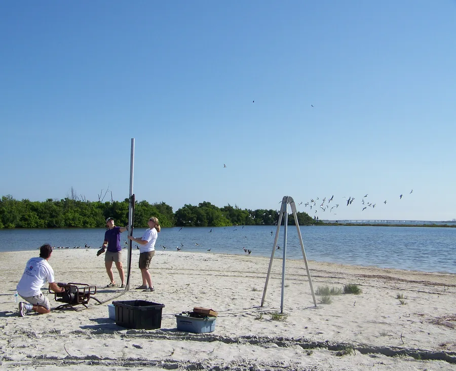 Staf lapangan USGS mengambil sampel sedimen memakai peralatan vibracoring di pantai