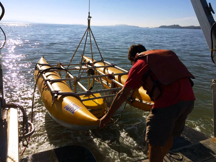 A chirp sub-bottom profiler transducer being deployed over the side of a survey vessel